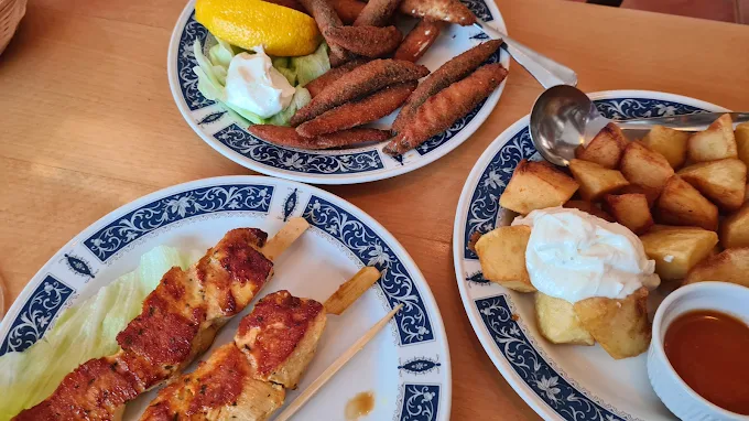 Selection of tapas — chicken skewers, patatas bravas and fried fish