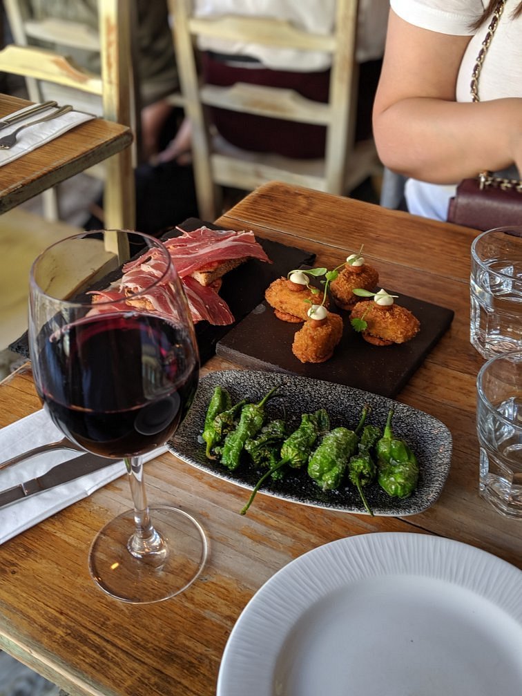 Spanish tapas board with jamón, croquetas, padrón peppers and red wine
