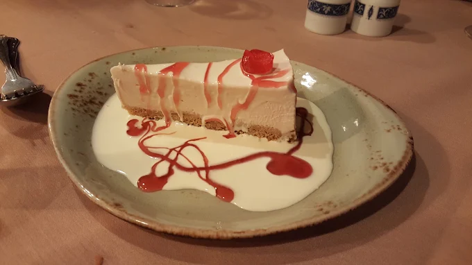 Slice of cheesecake with berry sauce and cream